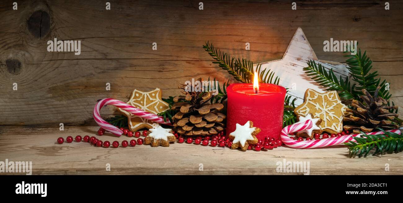 Candela rossa bruciante e decorazione per Natale e Avvento su tavole rustiche in legno in formato panoramico, spazio copia, fuoco selezionato, profondità di fi stretta Foto Stock