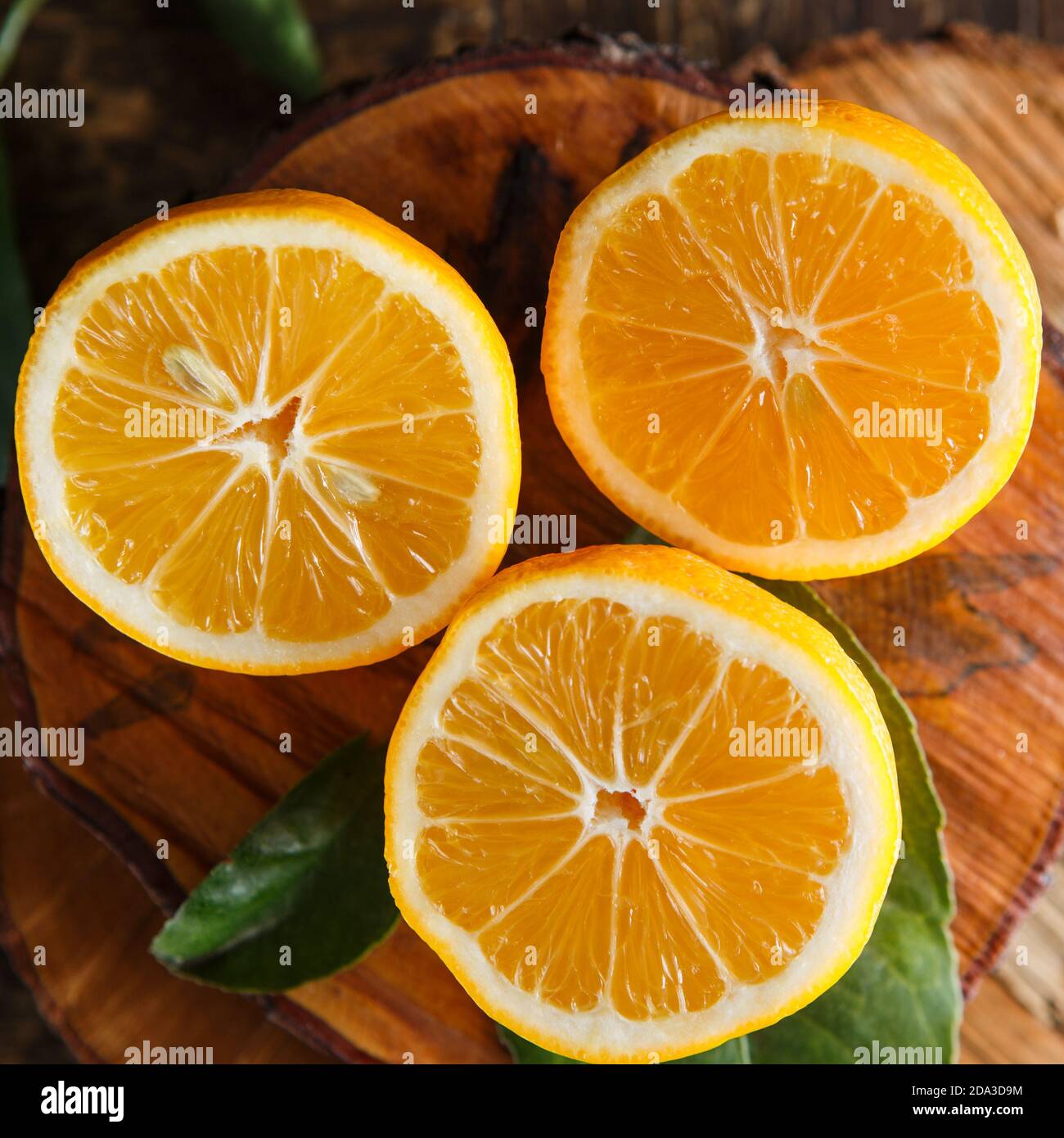 Tre metà di limone Meyer su un rustico asse di legno Foto Stock