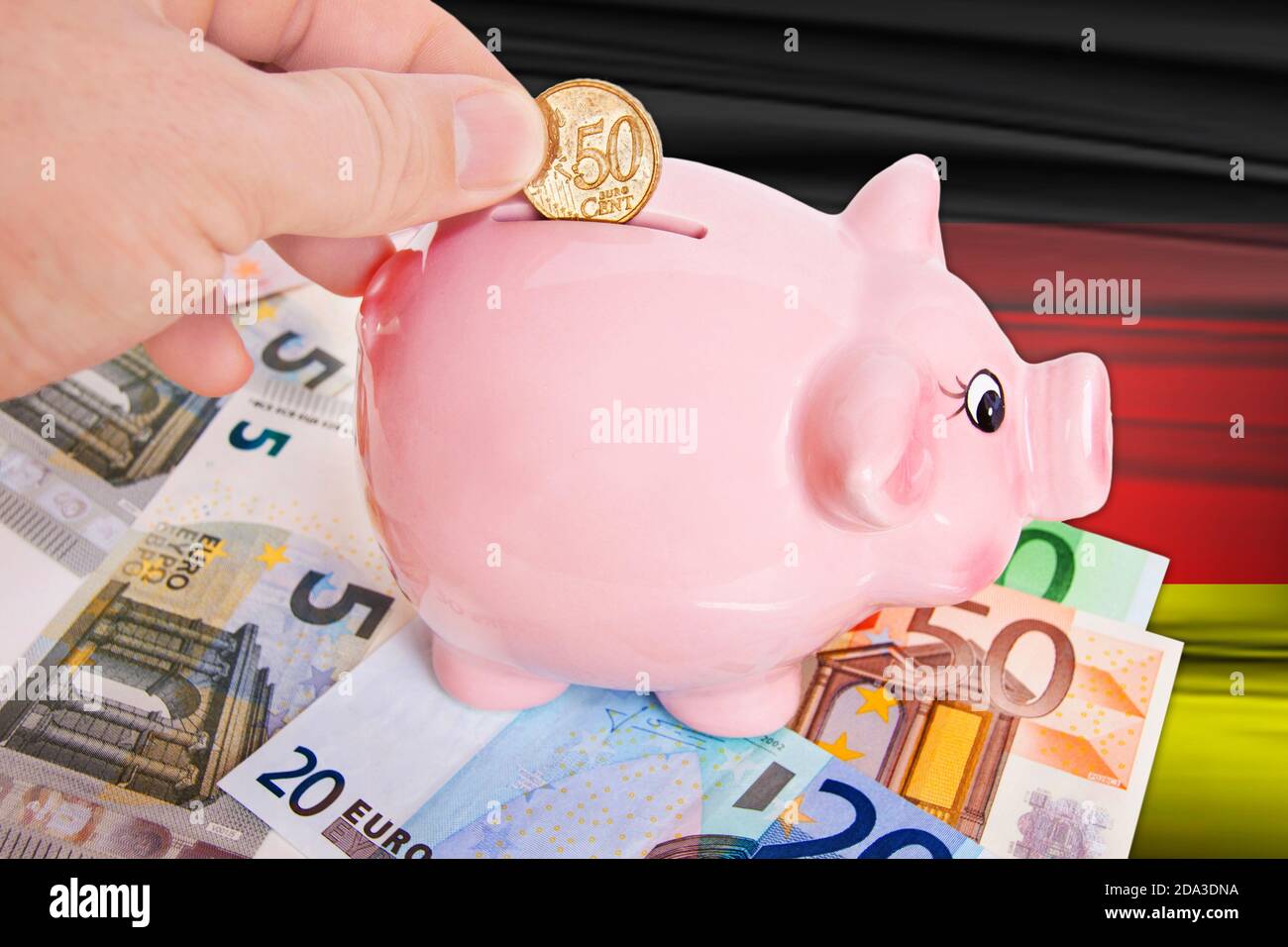 Sparschwein mit 50 cent Euromünze auf Deutschlandflagge Foto Stock