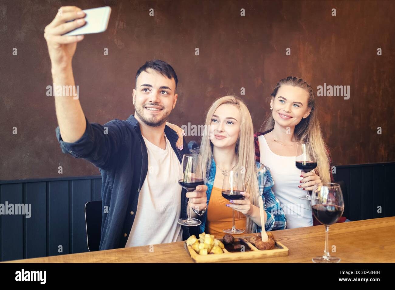 Felici i giovani amici che bevono vino selfie al ristorante Foto Stock