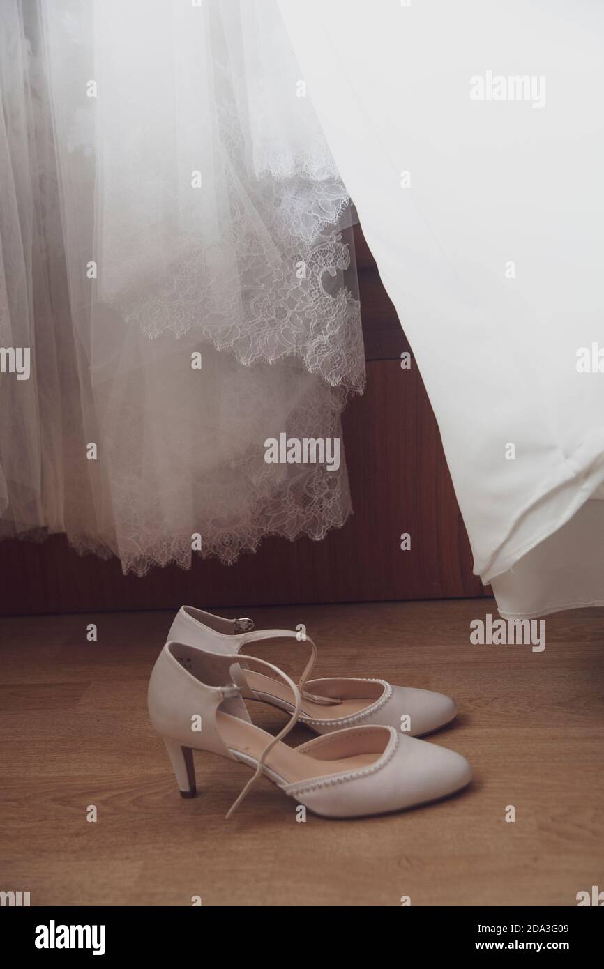 Scarpe da sposa bianche con un abito da sposa bianco lo sfondo Foto Stock