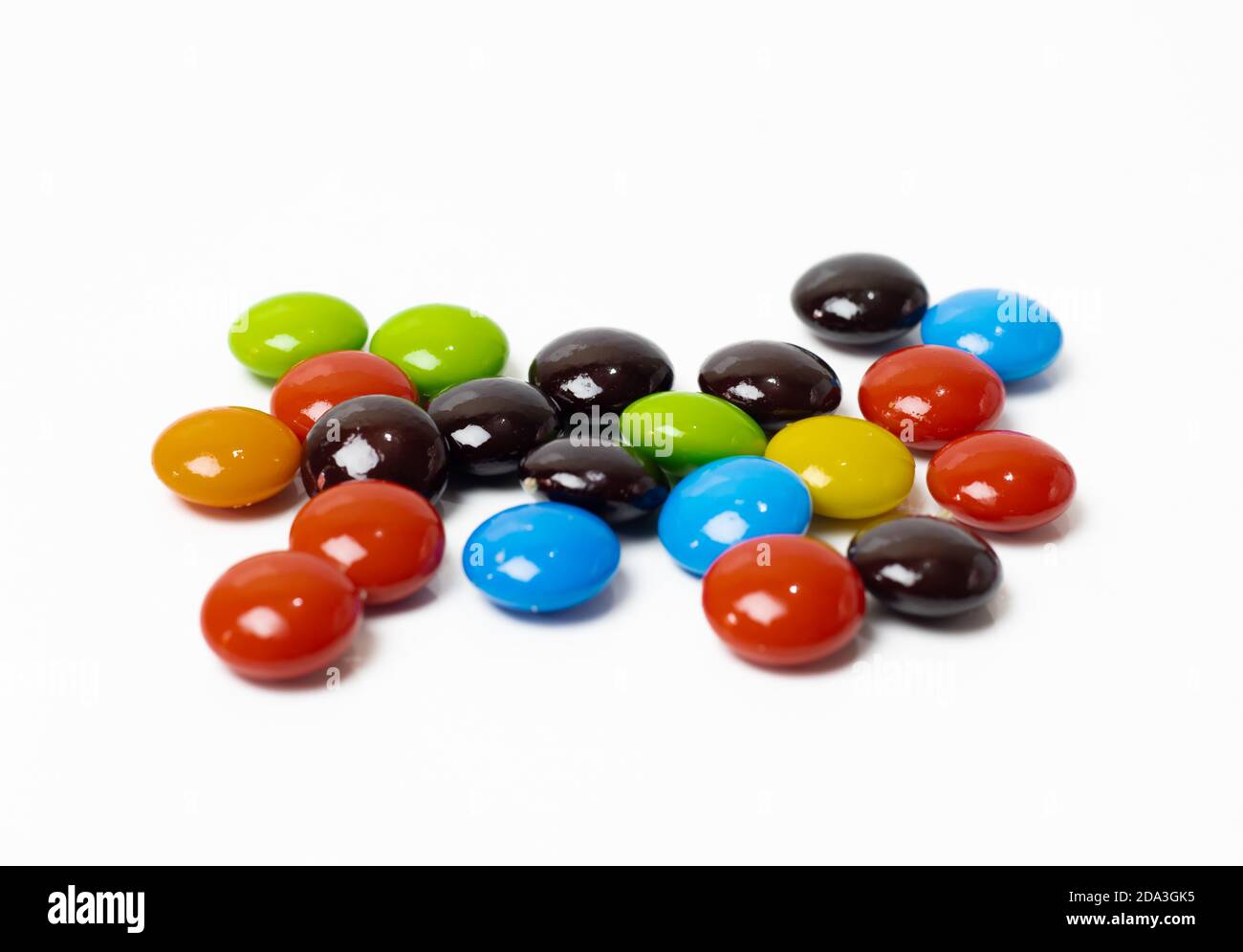 Le caramelle al cioccolato colorate sparse da vicino sembrano isolate su bianco sfondo Foto Stock