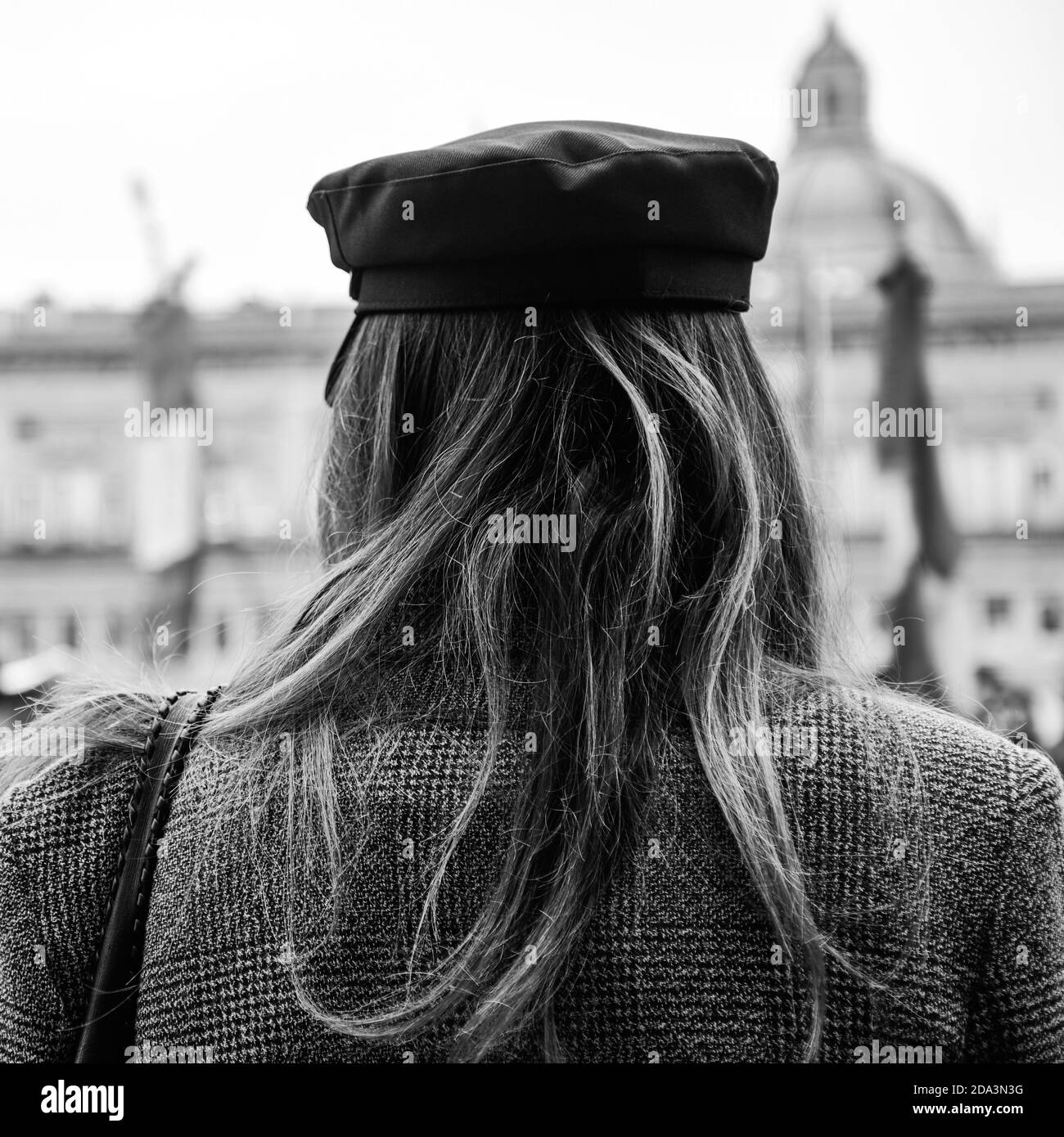 Vista posteriore di una donna alternativa che indossa cappotto vintage e marinaio cappello in piedi in una piazza durante una dimostrazione politica - Una donna attivista lotta per Foto Stock