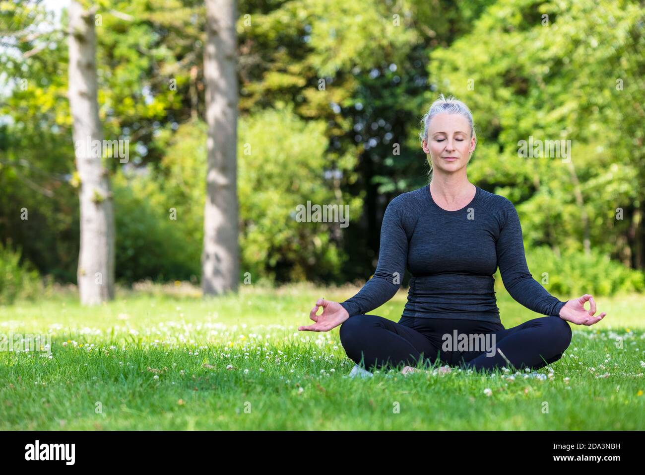 Mature metà età misura donna sana praticando yoga outsiin A. ambiente naturale tranquillo e verde Foto Stock