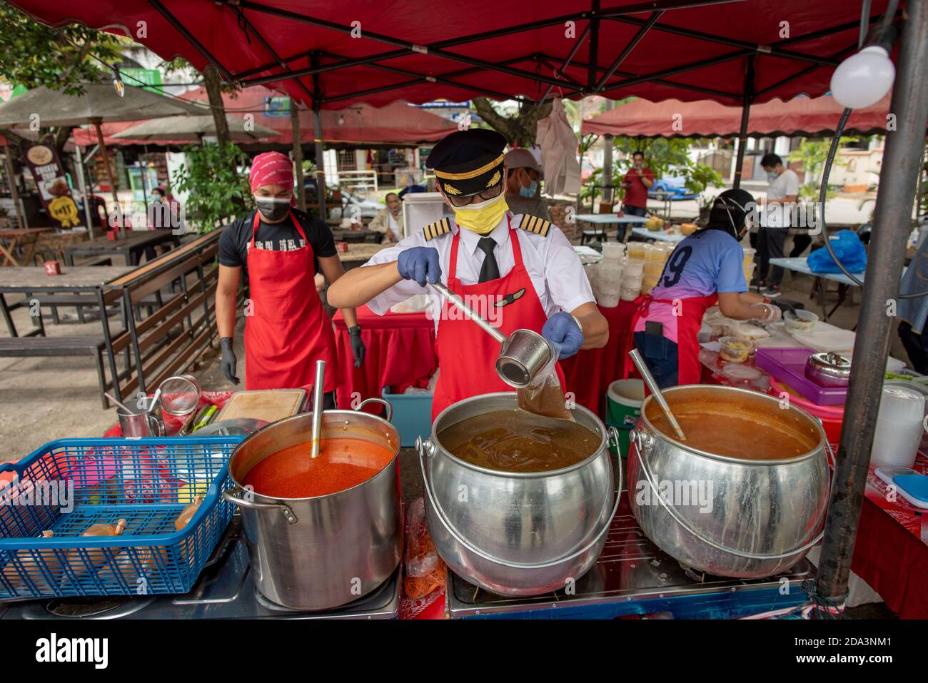 Subang Jaya, Malesia. 9 Nov 2020. Azrin Mohamad Zawawawi in uniforme pilota lavora nella sua stalla di cibo a Subang Jaya vicino Kuala Lumpur, Malesia, 9 novembre 2020. PER ANDARE CON 'Feature: Pilota malese 'vola' avanti con il proprio business dopo aver perso lavoro in mezzo COVID-19' Credit: Chong Voon Chung/Xinhua/Alamy Live News Foto Stock