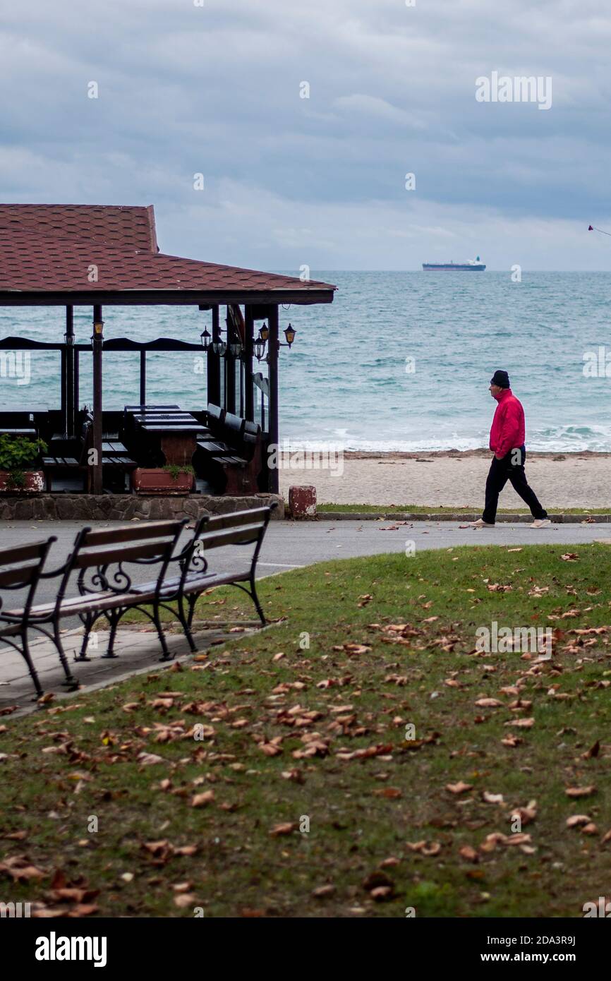 Burgas, Bulgaria - 9 novembre 2020: Un uomo cammina su una strada vicino a una spiaggia. Periodo invernale in autunno. Foto Stock