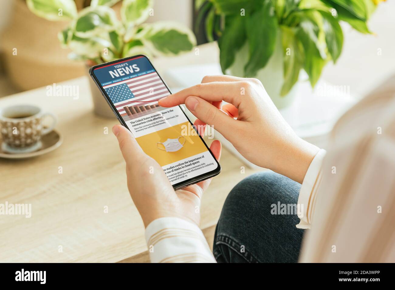 Foto d'archivio di una donna che legge notizie sul suo telefono nel soggiorno Foto Stock