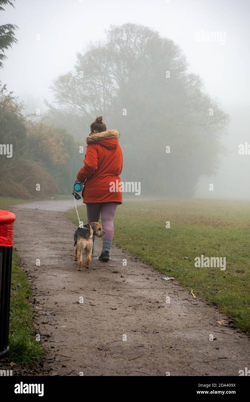Donna che cammina il suo cane nella nebbia di mattina presto Foto Stock