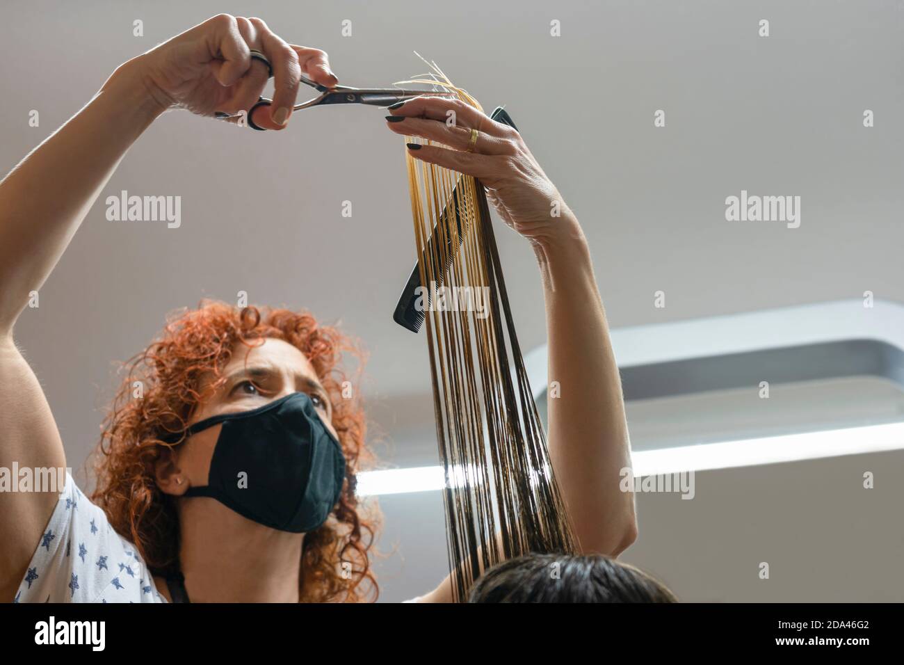 Professionale donna parrucchiere con maschera medica protettiva taglio capelli in parrucchiere.misure contro il coronavirus, covid-19.New lavoro normale Foto Stock