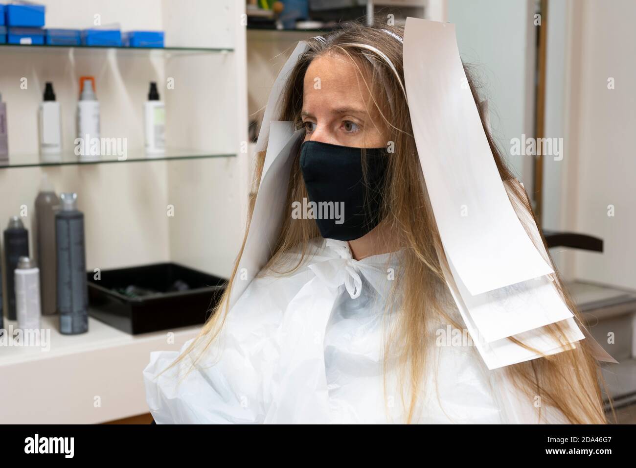 Bella donna cliente in parrucchiere, con carta tintura capelli per colorare i punti forti, trattamento colorante, indossare maschera medica contro coronavirus .Me Foto Stock