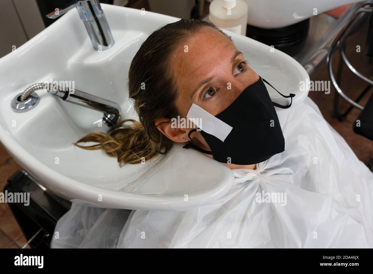 Donna che indossa una maschera medica di protezione al parrucchiere salon.customers , lavoratori e misure aziendali contro il concetto di coronavirus, nuova pandemia normale Foto Stock