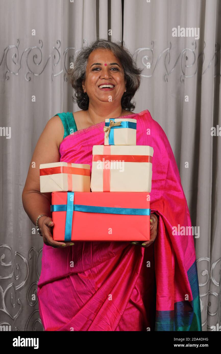 Ritratto di una donna indiana felice che tiene una pila di regali. Foto Stock
