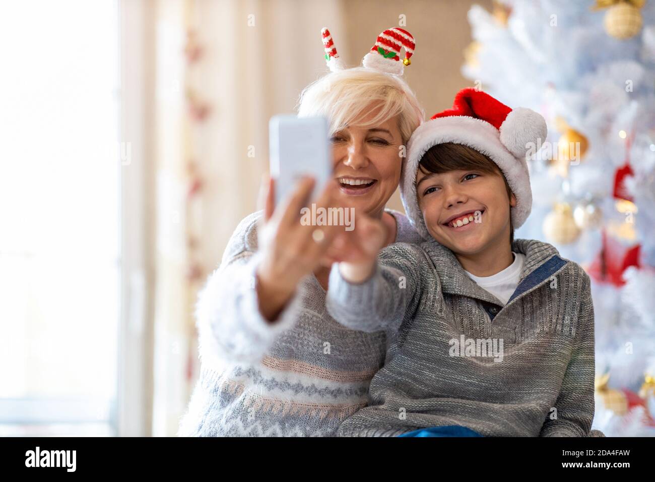 Madre e figlio che prendono selfie dall'albero di Natale Foto Stock