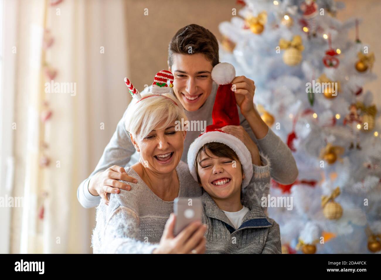 Madre e figli che prendono selfie a una festa di Natale a. casa Foto Stock