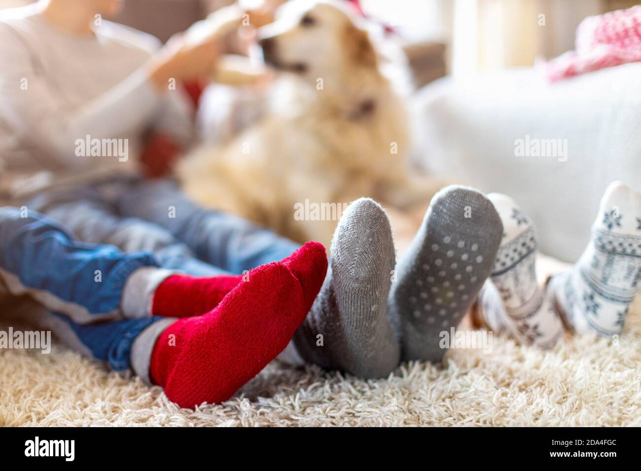 Famiglia in calze calde seduta in un'atmosfera accogliente di Natale A casa Foto Stock