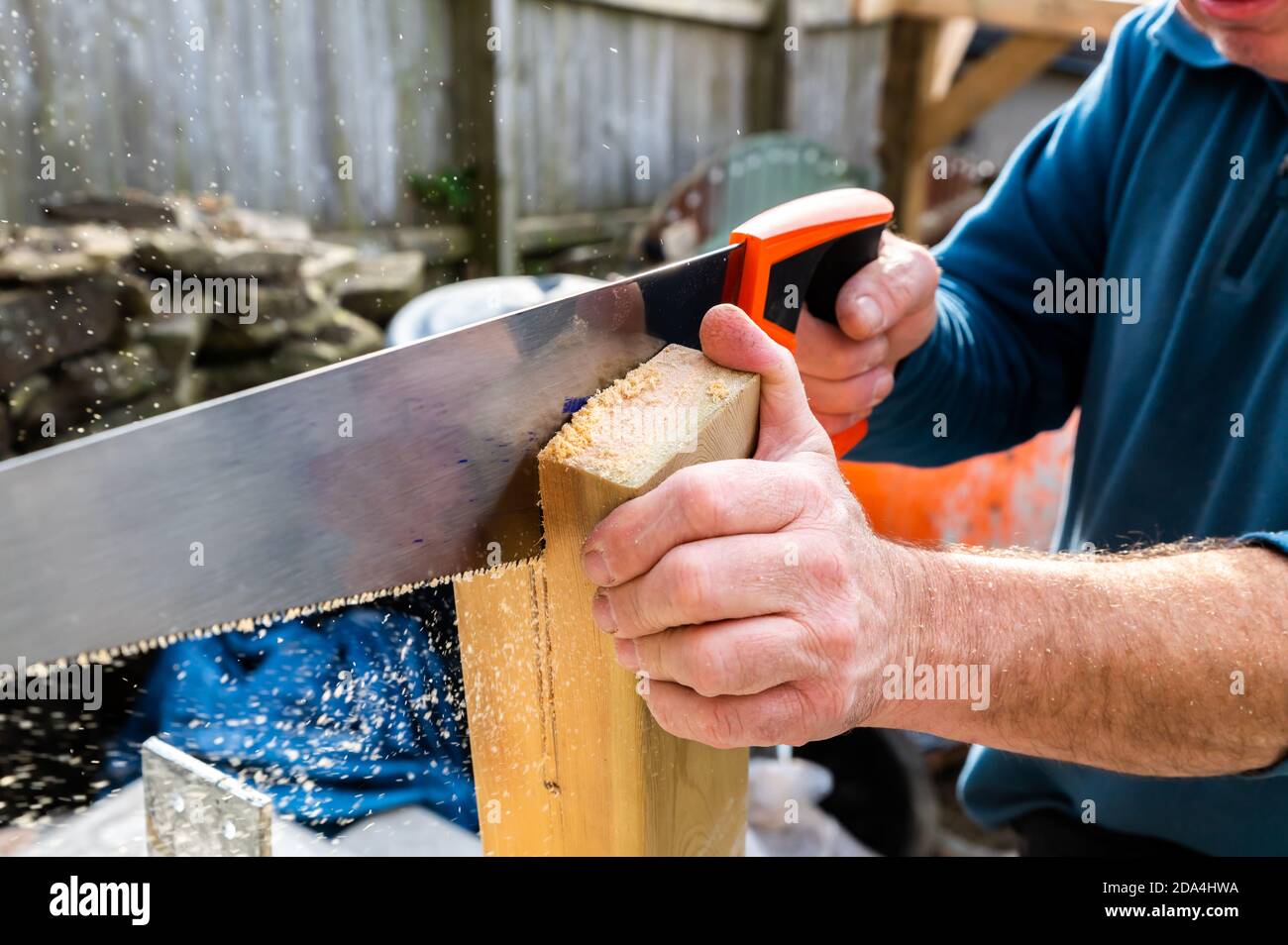 Manipolo con sega manuale che taglia una fessura nel corrimano montante da montare sulla staffa Foto Stock