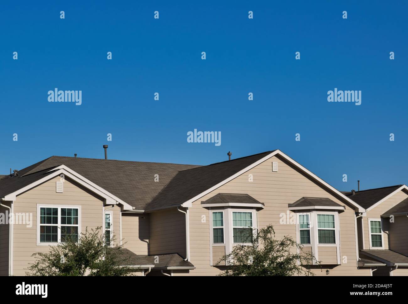 Townhome tetti nei sobborghi in una suddivisione della città sotto un cielo blu chiaro con spazio di copia sopra. Foto Stock