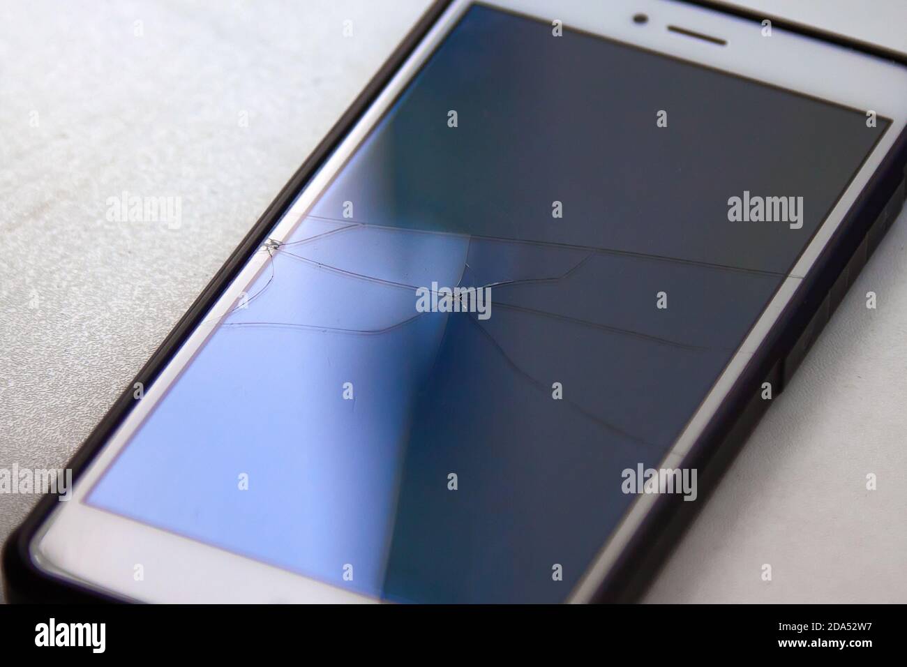 Evidenziazioni colorate dello schermo di un telefono cellulare rotto in riflesso della luce del giorno Foto Stock