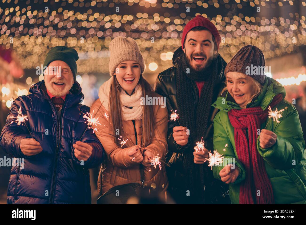 Ritratto di bella bella allegra allegria allegra famiglia divertendosi visita il mercato urbano di strada conto alla rovescia celebrazione di mezzanotte bruciando festale bengala fuoco Foto Stock