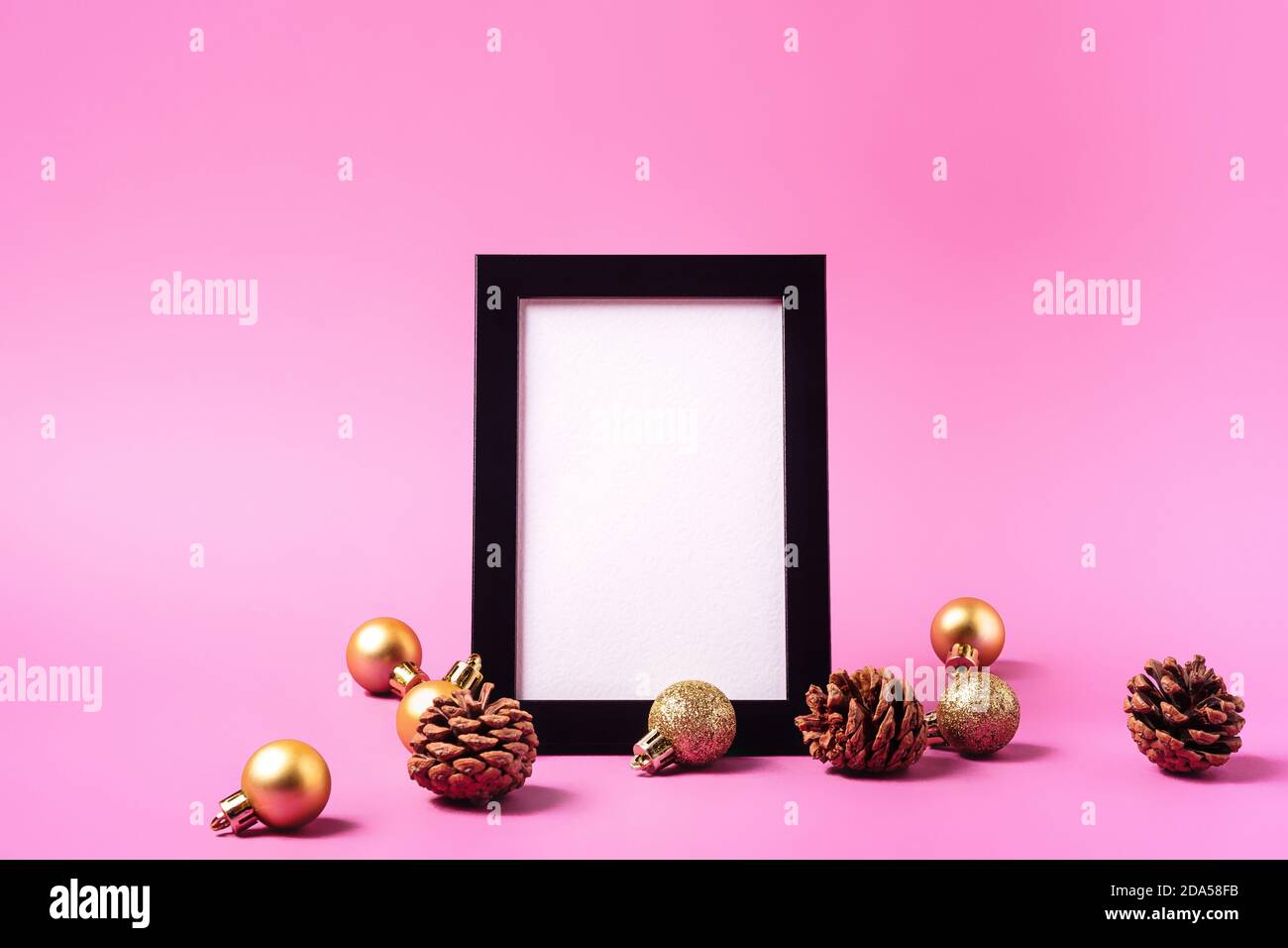 Natale composizione minima con cornice vuota. Ornamento dorato, decorazioni con coni di pino. Modello di biglietto di auguri mock-up Foto Stock