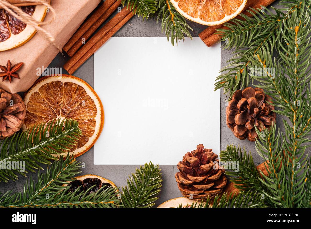 Composizione di Natale mockup. Confezione regalo, cannella, anice, frutta secca, coni di pino e decorazioni con aghi di abete su sfondo grigio Foto Stock