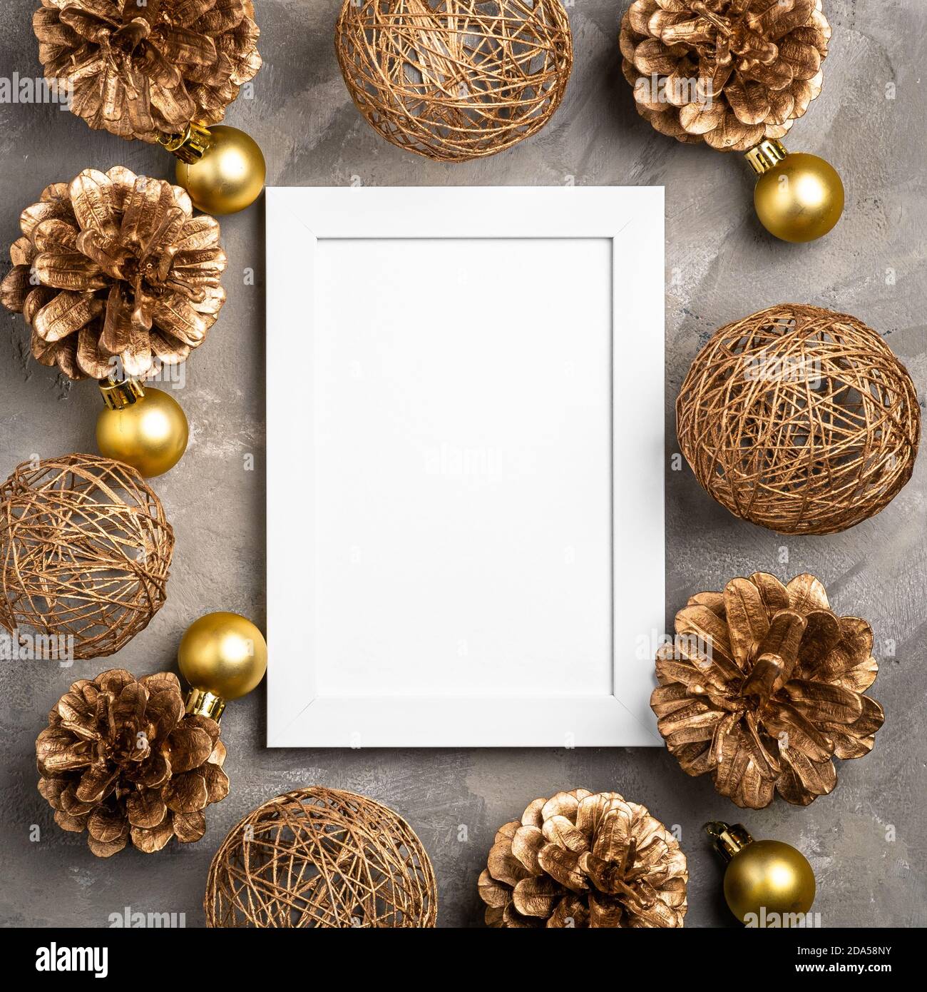 Composizione natalizia con cornice vuota. Ornamento dorato, decorazioni con coni di pino. Modello di biglietto di auguri mock-up Foto Stock