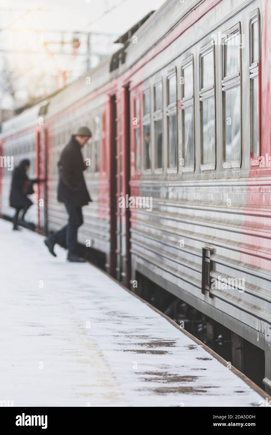 Una silhouette di passeggeri sfocati entra in treno in inverno, all'aperto. Trasporto passeggeri in città Foto Stock