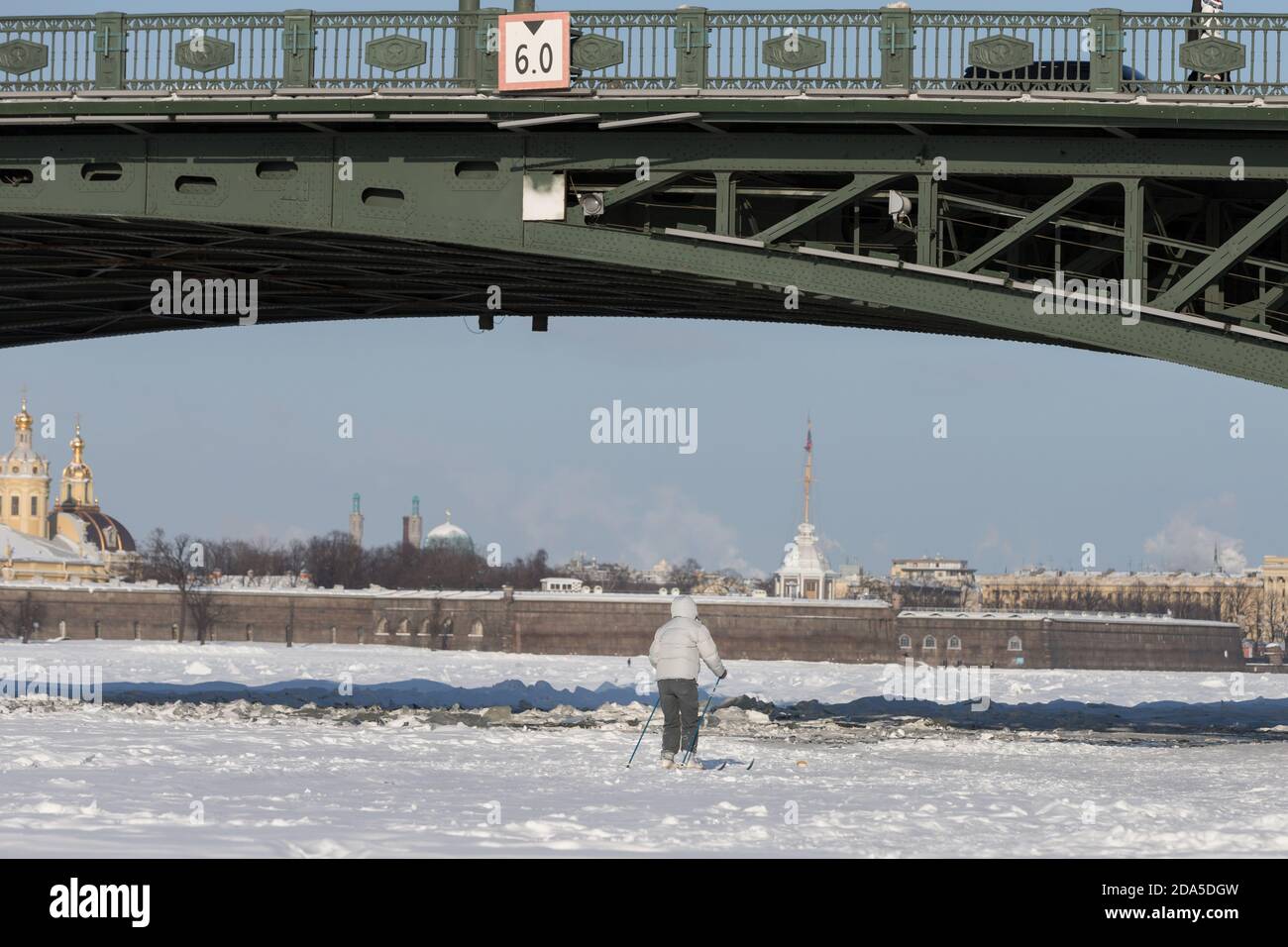 Silhouette di sciatore che cavalcano sul ghiaccio della Neva congelata Fiume sotto il Palace Bridge in inverno al tramonto Foto Stock