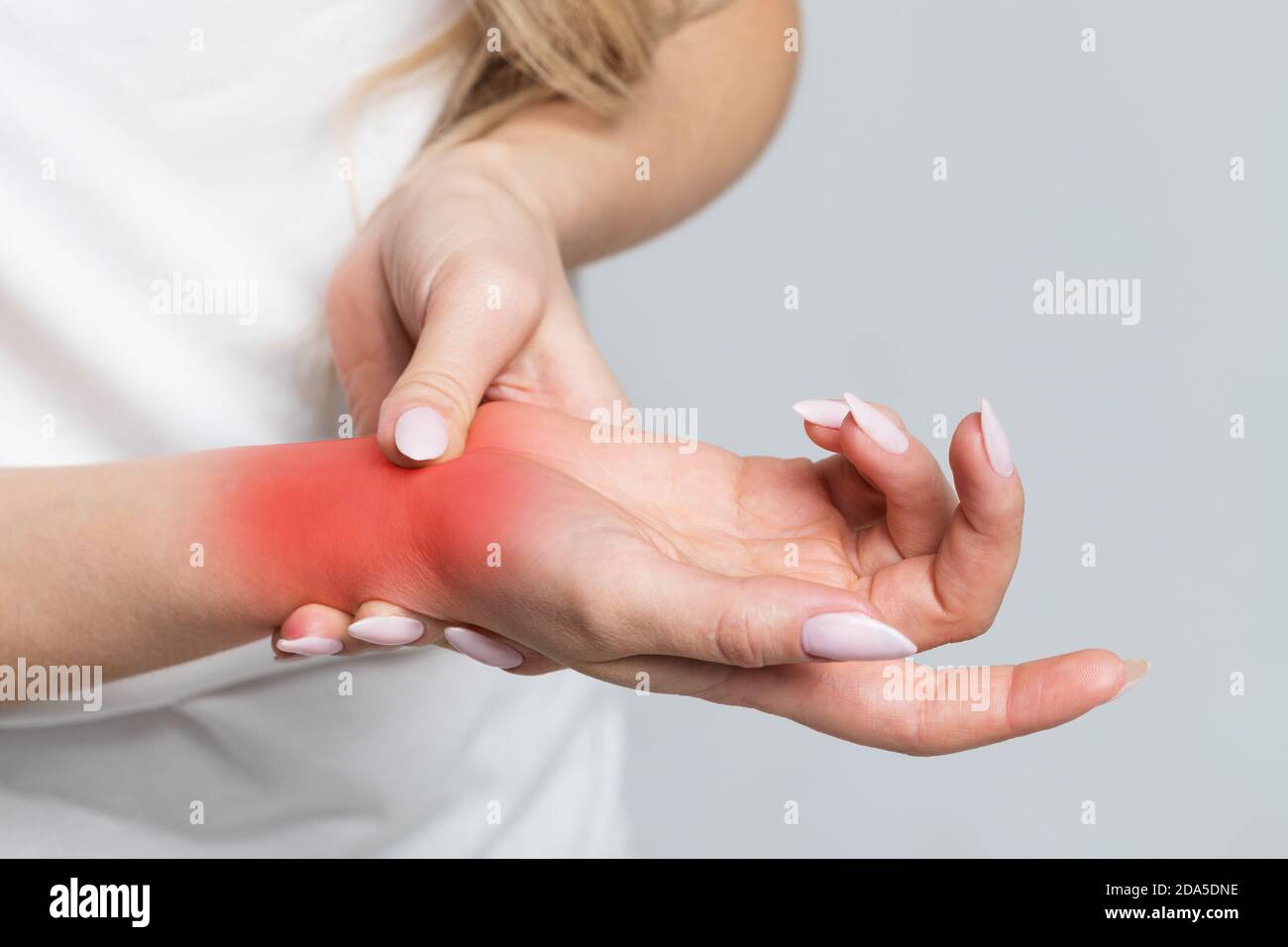Closeup del braccio femminile che tiene il suo polso doloroso causato da lavoro prolungato sul computer, laptop / sindrome del tunnel carpale, artrite, malattie neurologiche Foto Stock