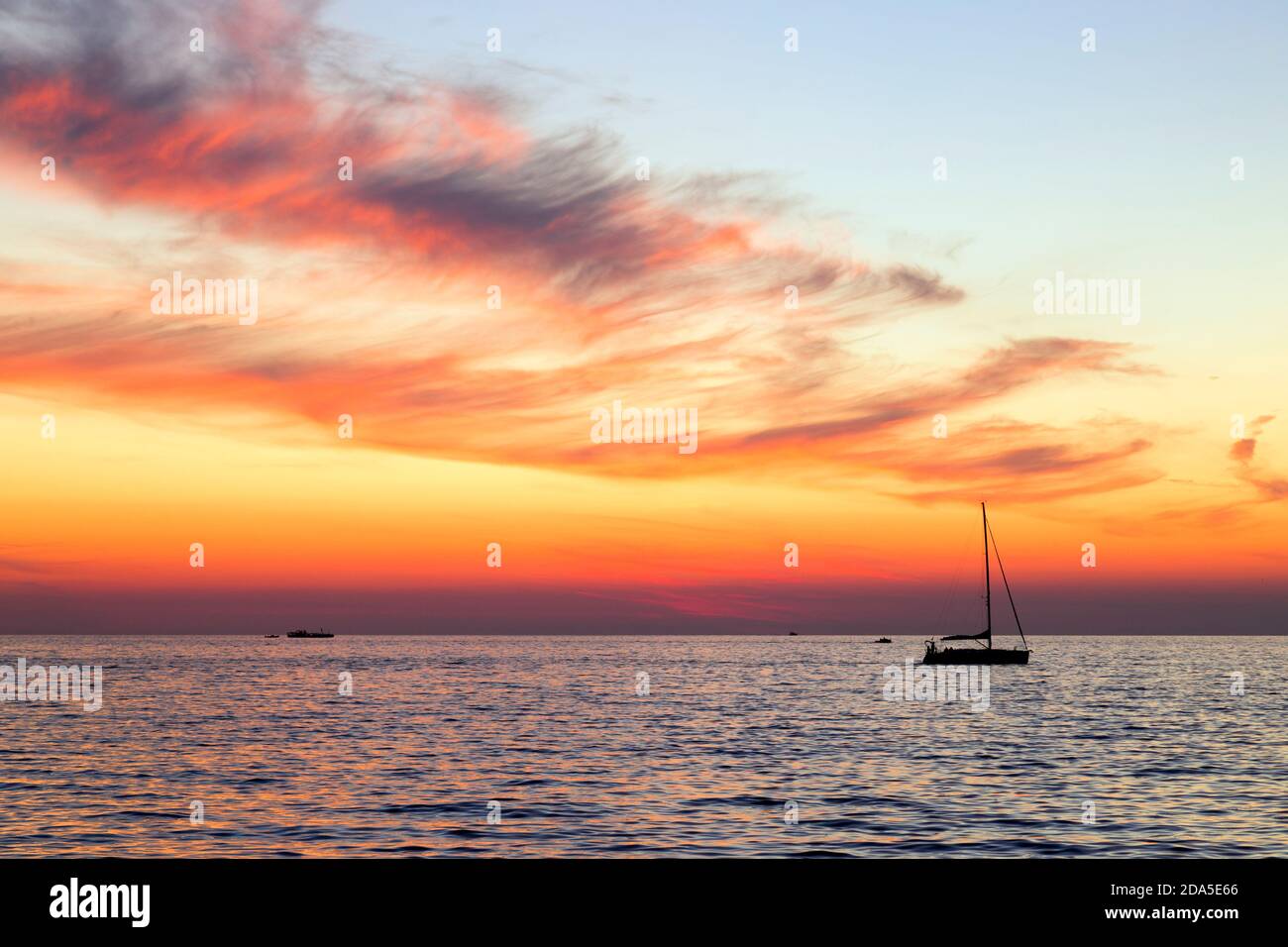 Una barca singola in una colorata serata al tramonto, nell'oceano Adriatico al largo della costa di Rovigno, Croazia in Europa orientale. Foto Stock