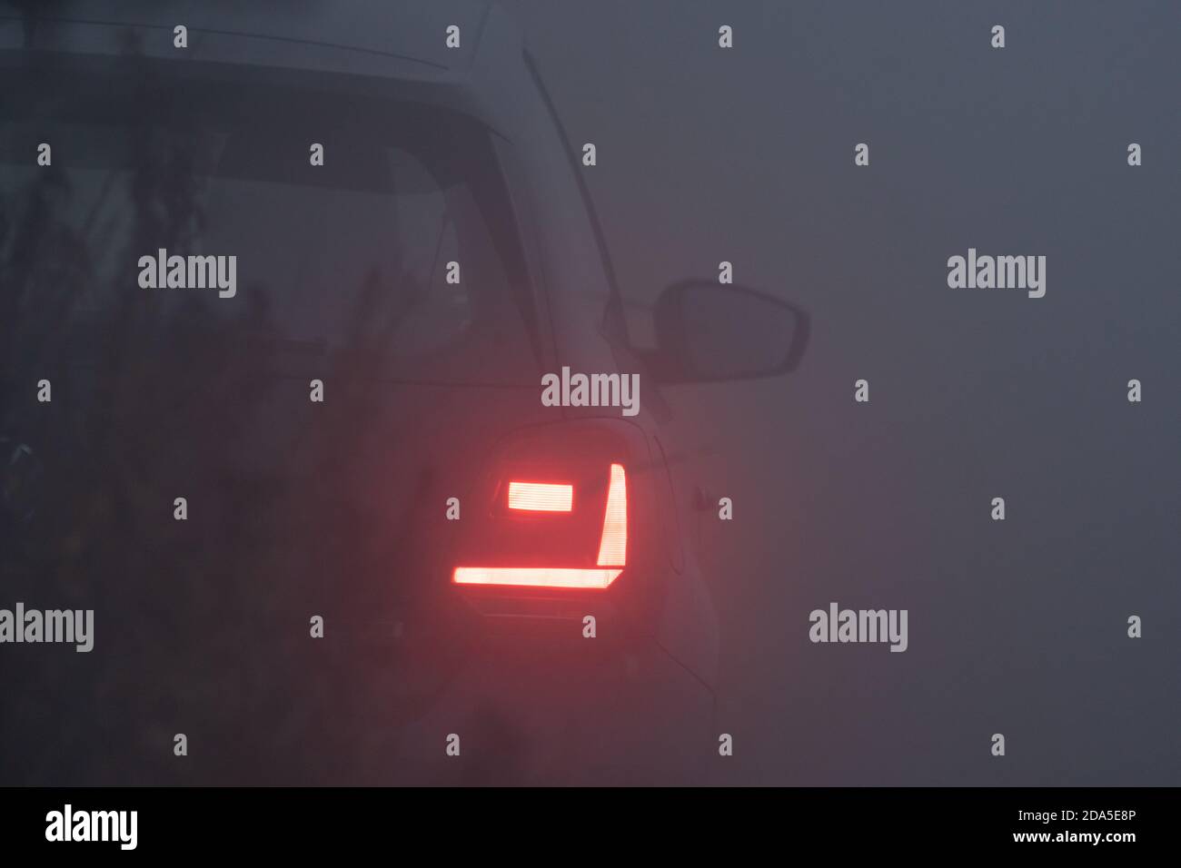 Luci di coda di un'auto in nebbia fitta, ora blu, sera nebbia, notte nebbia, auto Foto Stock