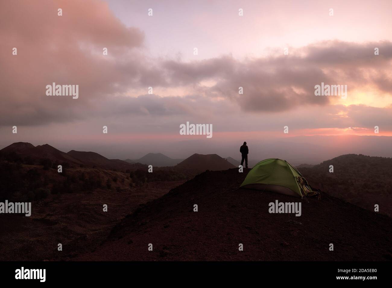Uomo che guarda l'alba da un'area selvaggia di antichi vulcani nel Parco Nazionale dell'Etna, in Sicilia Foto Stock