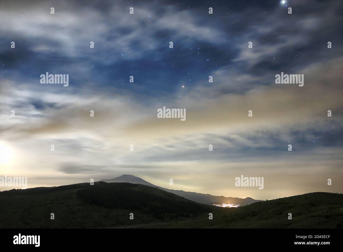 Nuvole e luna sorgono nel cielo stellato sull'Etna, in Sicilia Foto Stock