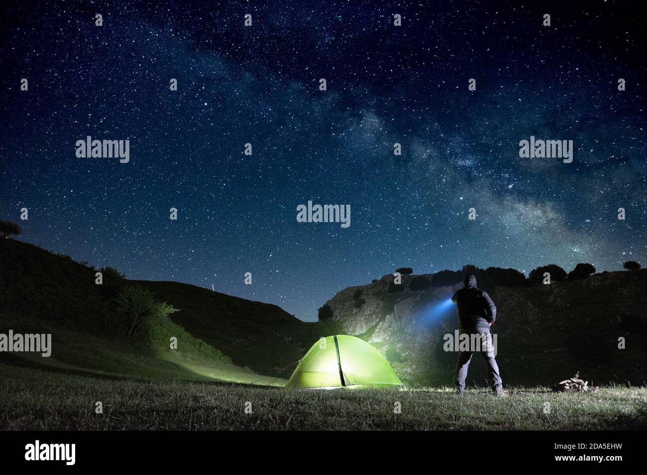 Uomo che punta la torcia blu alla montagna sotto il cielo stellato nel Parco dei Nebrodi, Sicilia Foto Stock