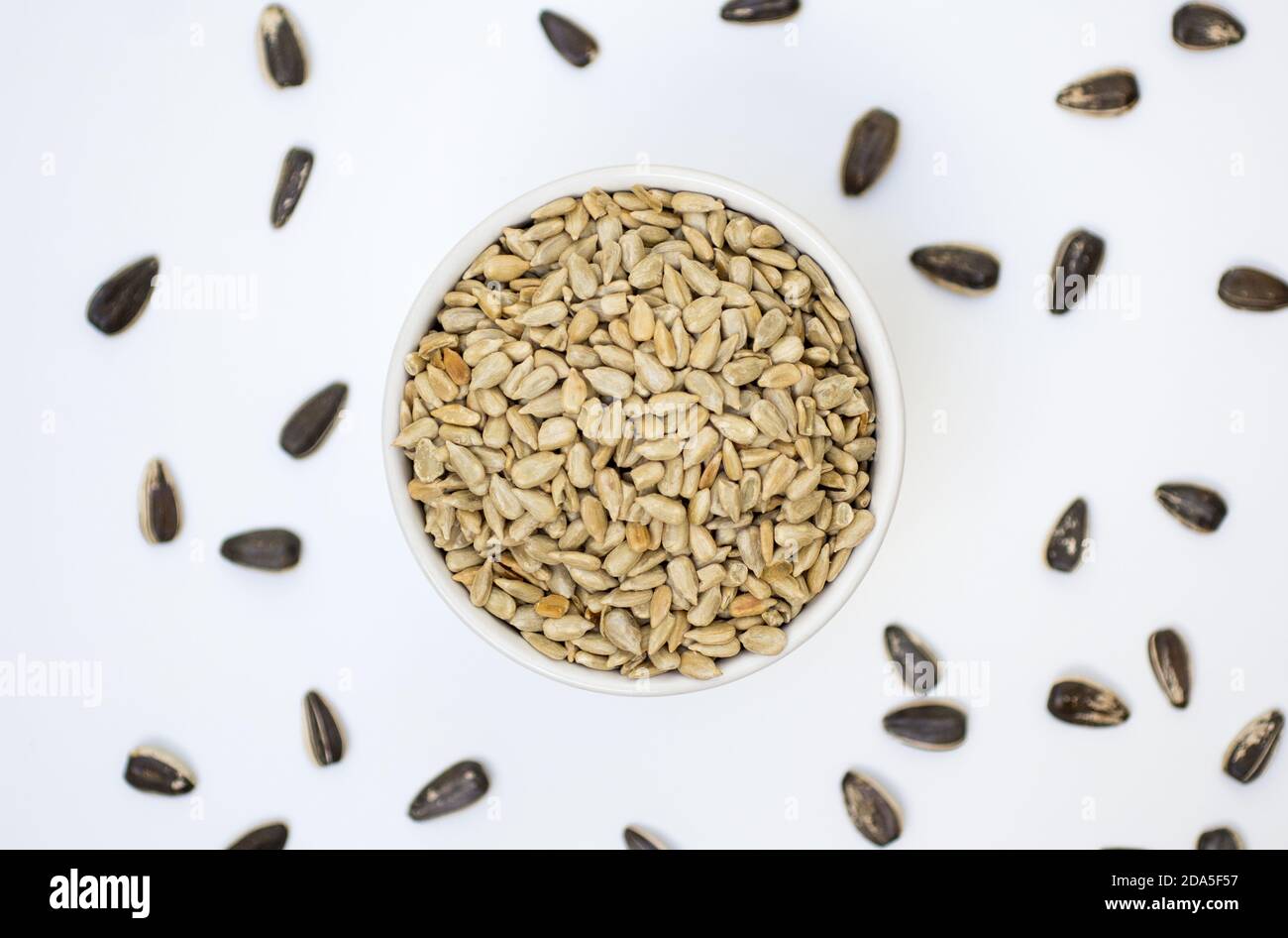 Semi di girasole su una ciotola con sfondo bianco. Cibo vegetariano sano Foto Stock