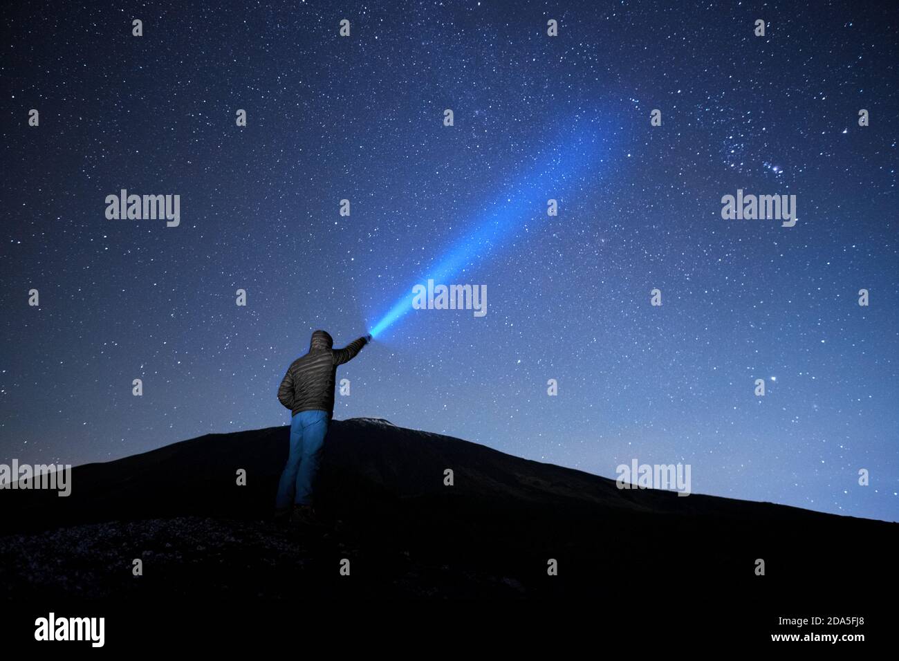 Uomo che punta la torcia blu al cielo stellato nel Parco dell'Etna, Sicilia Foto Stock