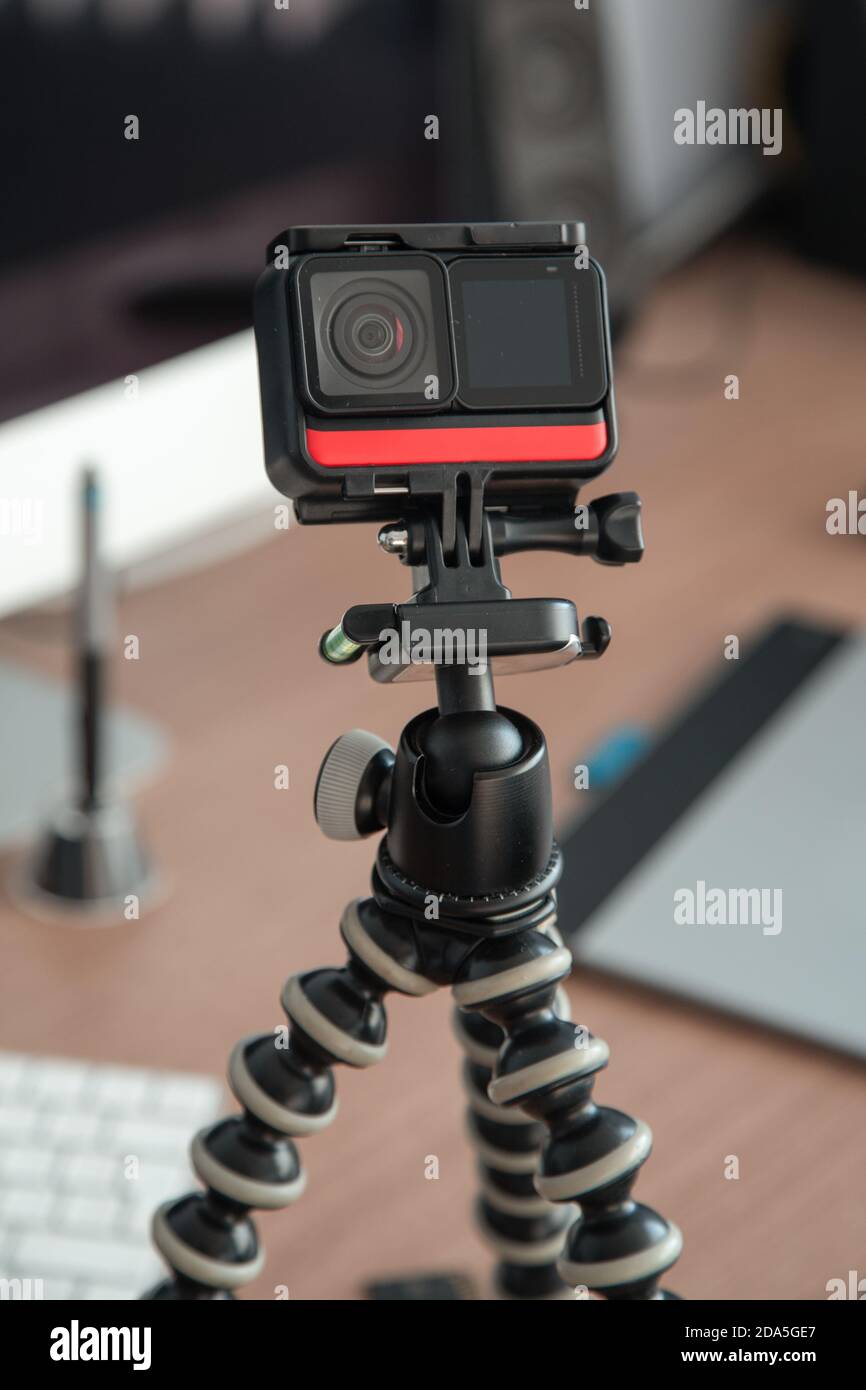 dettagli di una piccola fotocamera portatile su un treppiede con un microfono, sfondo alcuni elementi dell'ufficio Foto Stock