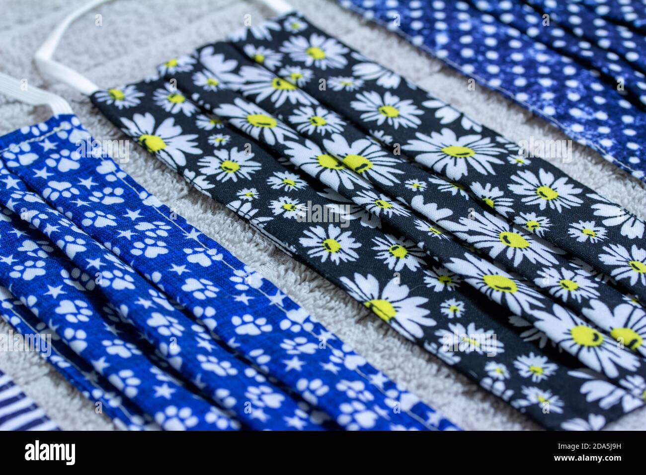Primo piano di quattro diverse maschere facciali COVID lavate a mano, asciugando su un asciugamano di cotone sul tavolo da cucina Foto Stock