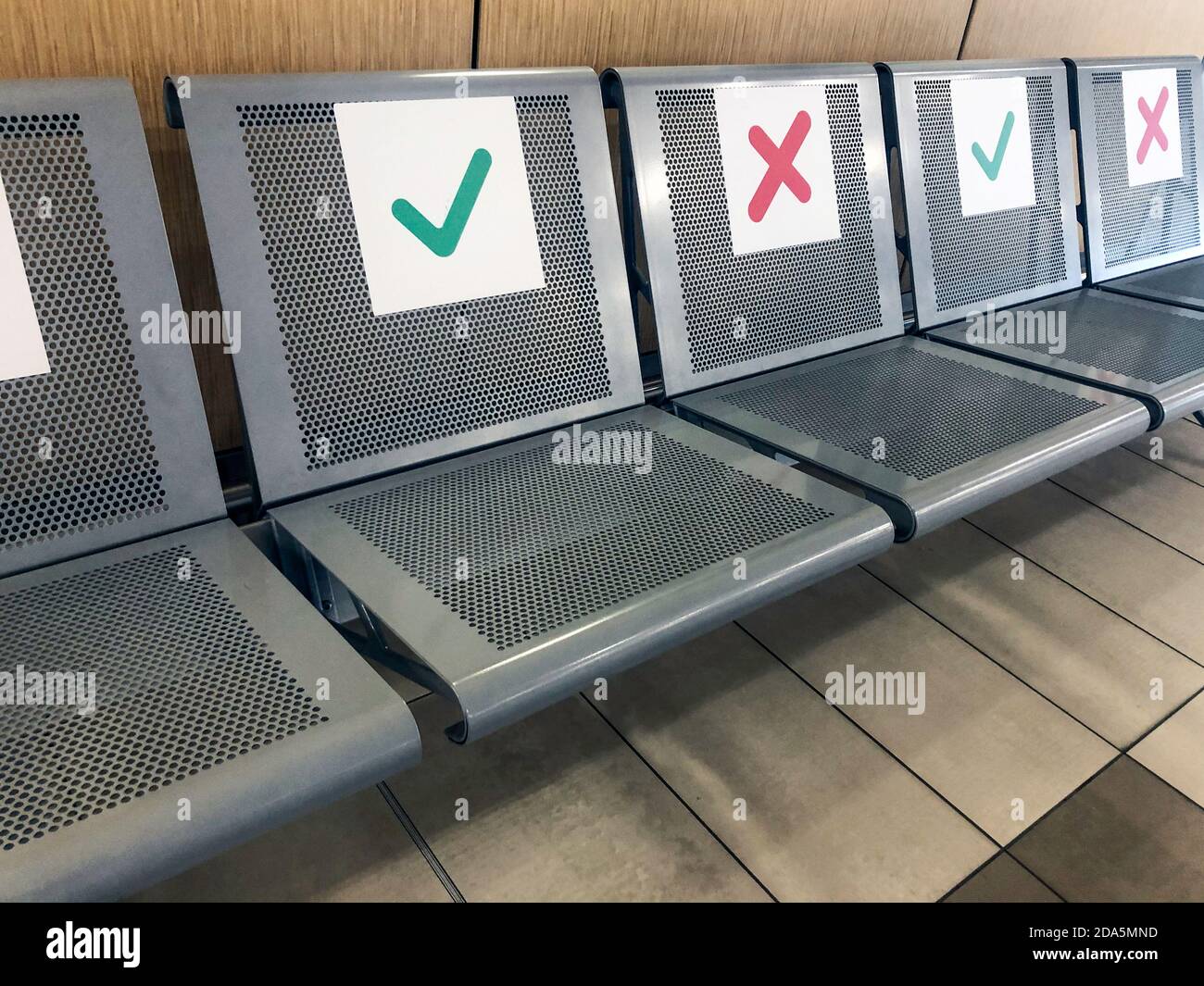 Fila di sedie vuote con indicazione di dove è giusto sedersi per mantenere la sicurezza sociale Distanza durante il periodo del COVID-19 coronaviru Foto Stock