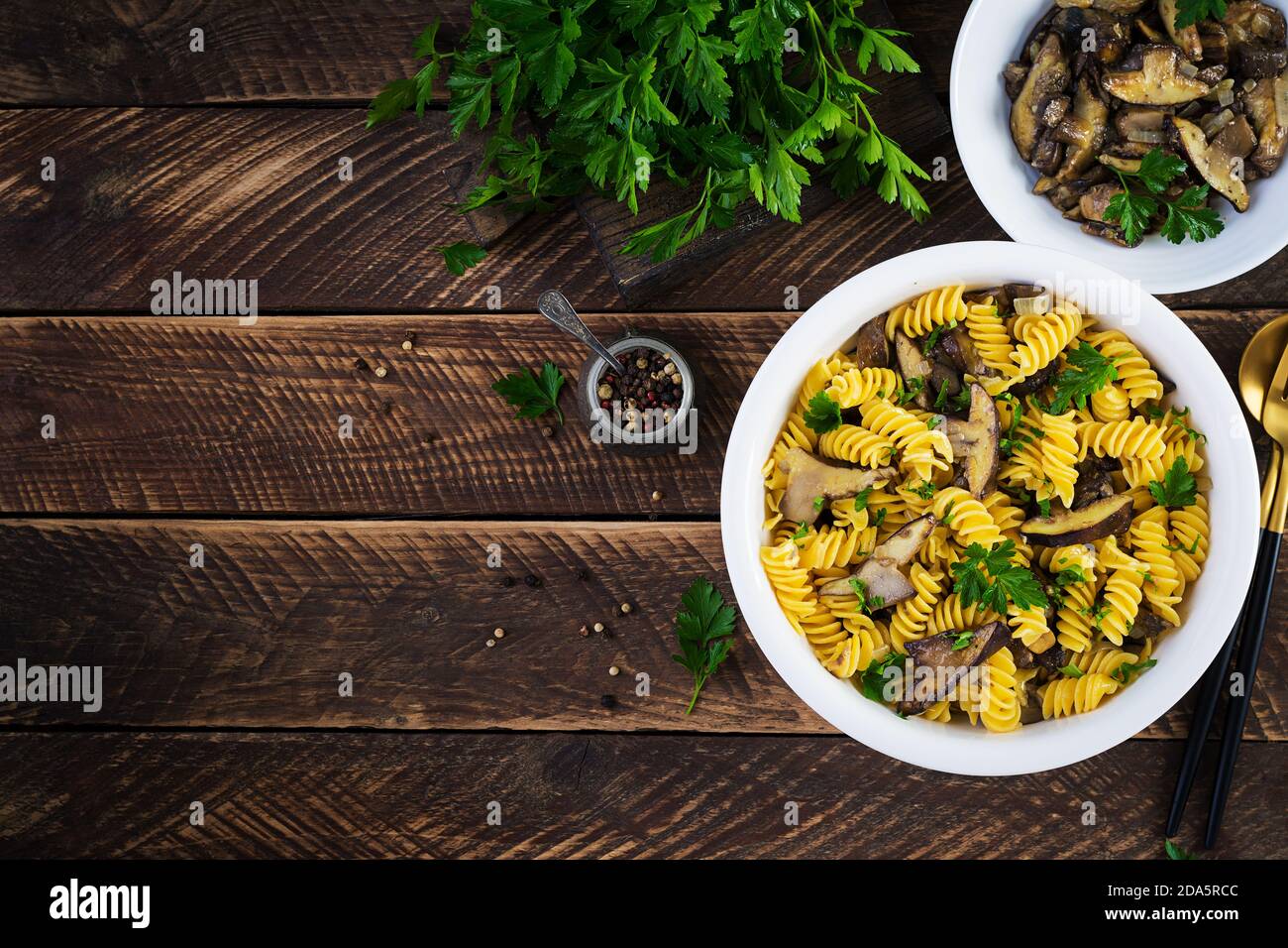 La pasta dei fusilli è priva di glutine con funghi di bosco su un piatto bianco. Cibo vegetariano / vegano. Cucina italiana. Vista dall'alto, disposizione piatta, spazio per la copia Foto Stock