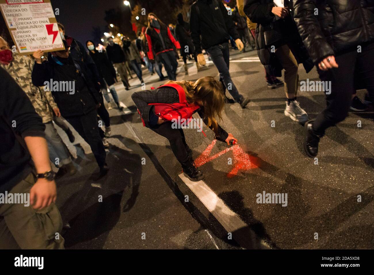 Un protestante dipinge sulla strada il fulmine rosso - simbolo dello sciopero femminile e della resistenza durante la marcia.gli oppositori della sentenza della Corte costituzionale sull'aborto protestarono ancora una volta. Centinaia di persone si sono riunite al di fuori del Ministero dell'Educazione Nazionale per chiedere le dimissioni del Ministro dell'Istruzione e della Scienza, Przemyslaw Czarnek, noto per le sue dichiarazioni pubbliche omofobiche e sciovinistiche. In diverse occasioni, la polizia disperse con forza i manifestanti che avevano cercato di bloccare il traffico e marciavano inaspettatamente attraverso il centro della città. Numerosi manifestanti sono stati deta Foto Stock
