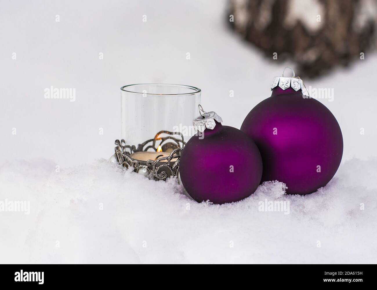 Palle di Natale viola e candela nella neve; concetto di carta di natale Foto Stock