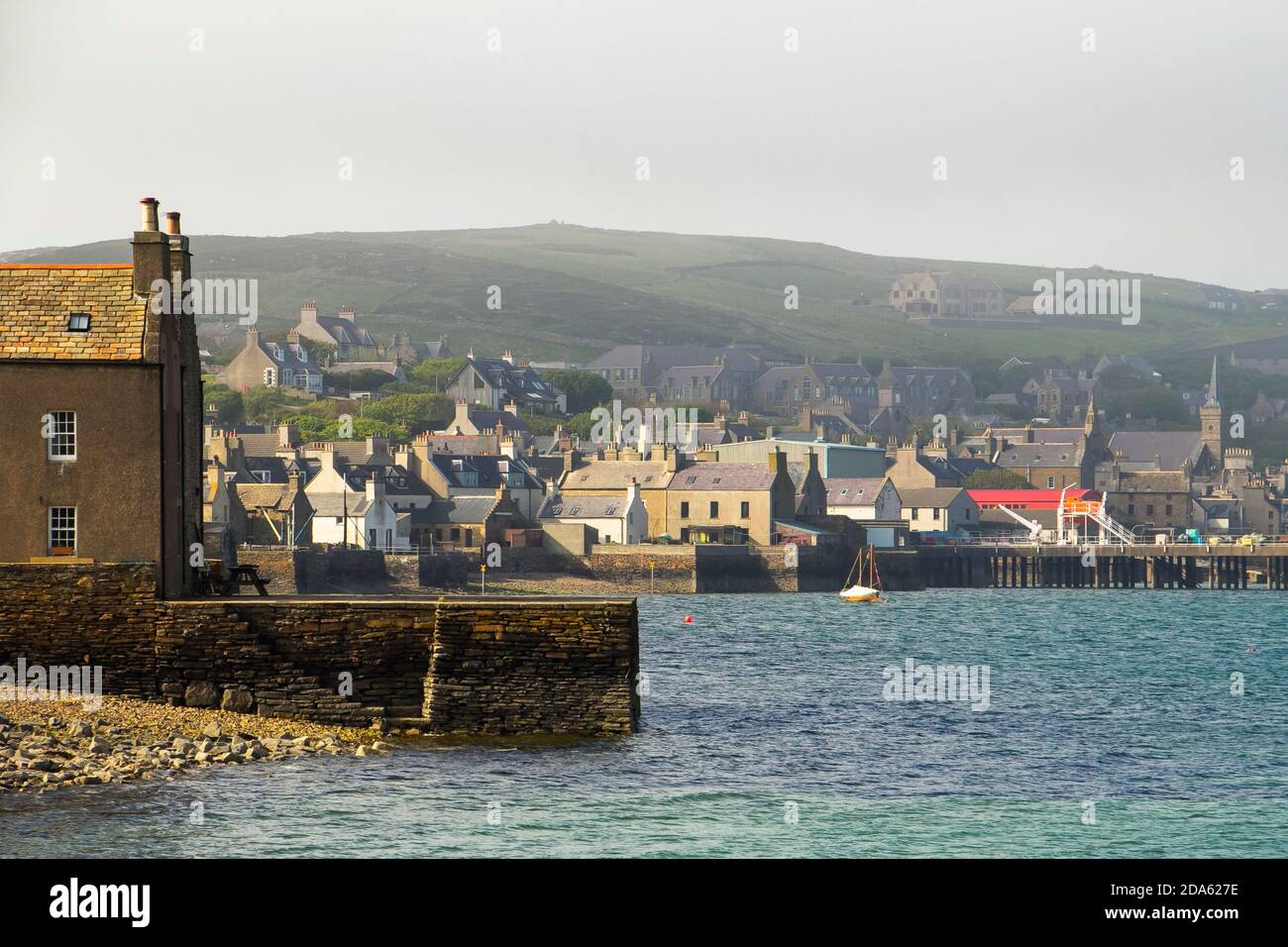 Vista sul lungomare delle case e della collina nella città portuale di Orkney Di Stromness Foto Stock