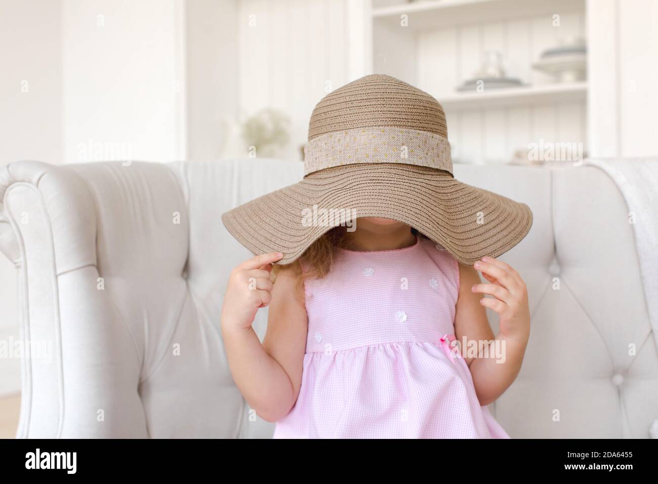 Cute ragazza nascondendo faccia dietro cappello di paglia Foto Stock