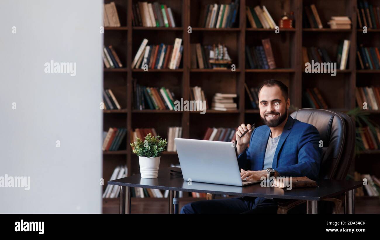 Un giovane uomo d'affari in ufficio della biblioteca è seduto a una scrivania . un uomo sta lavorando su un portatile Foto Stock