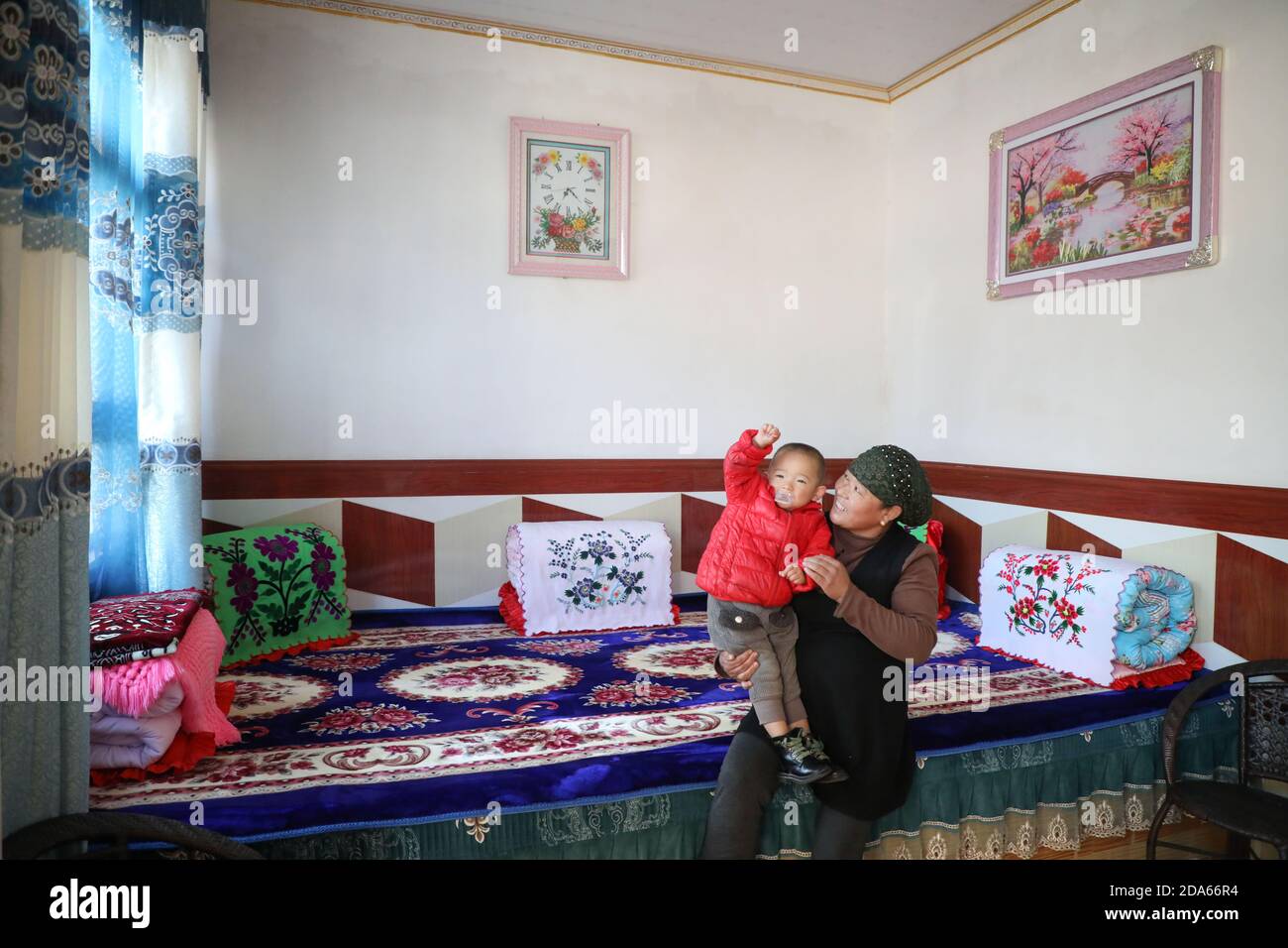 (201110) -- DONGXIANG, 10 novembre 2020 (Xinhua) -- UN villager gioca con il suo nipote al Villaggio di Bulenggou nella Contea Autonoma di Dongxiang della Prefettura Autonoma di Linxia Hui, nella provincia di Gansu, nella Cina nord-occidentale, il 9 novembre 2020. Bulenggou Village era un'area gravemente impoverita. Fin dall'inizio del lavoro di alleviamento della povertà, il villaggio è cambiato insieme a migliori infrastrutture, che consentono agli abitanti del villaggio di accedere all'acqua potabile, alle strade, al centro sanitario e alla scuola primaria ben attrezzata. L'allevamento di bestiame è diventato l'industria leader del Villaggio di Bulenggou, dove gli abitanti del villaggio ne hanno assistito Foto Stock