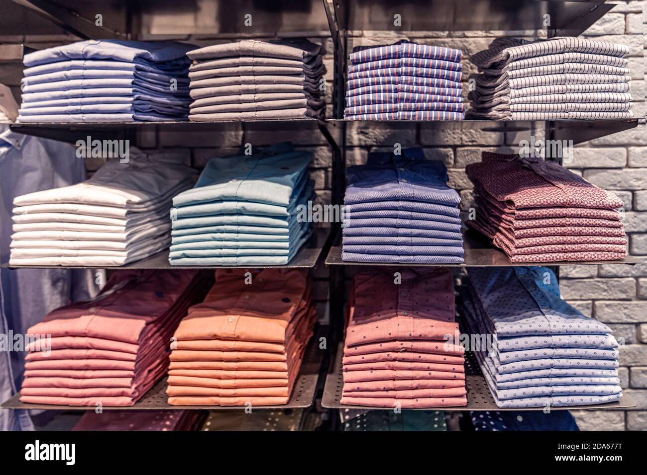 Vestiti esposti in negozio, camicie da uomo di diversi colori sullo scaffale, splendidamente e ordinatamente disposti in pile Foto Stock