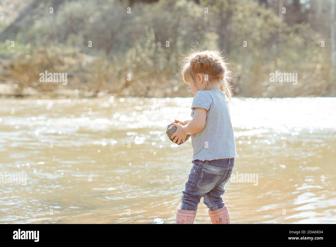 bambina che gioca con le rocce vicino al fiume Foto Stock