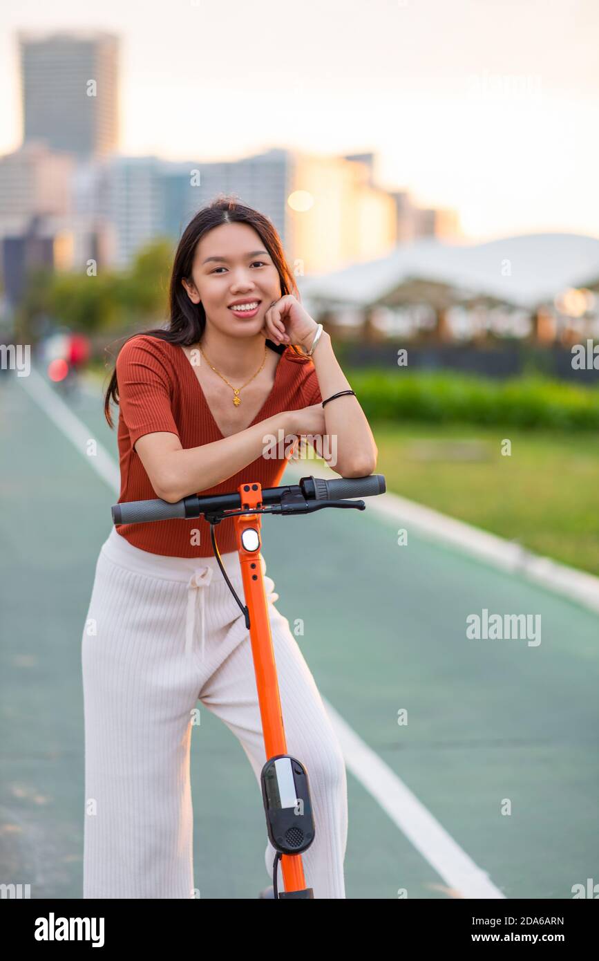 Donna che ha un giro su scooter elettrico per veloce e. facile trasporto in una moderna vita cittadina Foto Stock