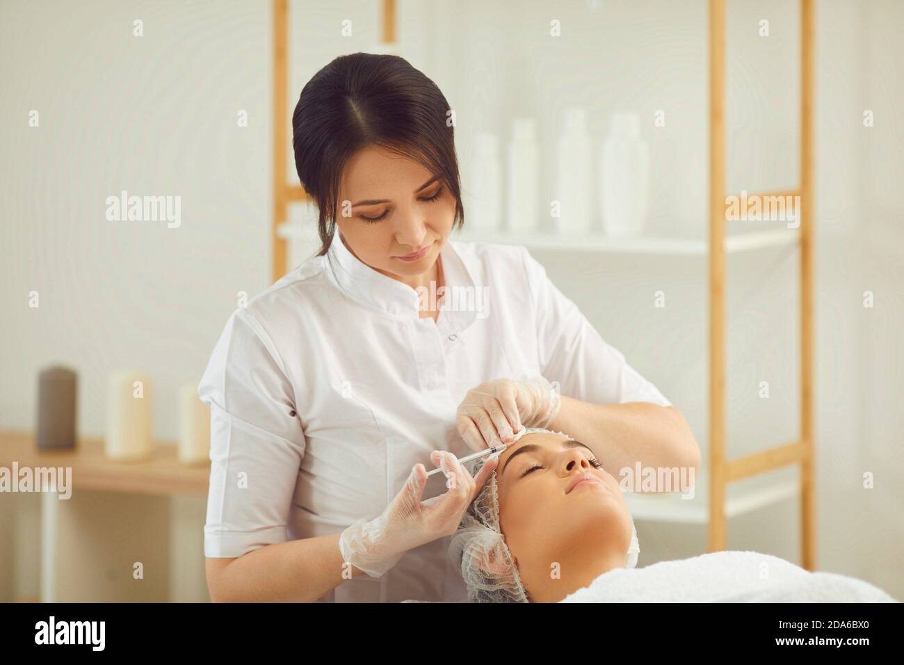 Donna dermatologist che fa l'iniezione del riempitivo del botox anti-invecchiamento alla fronte del womans Foto Stock